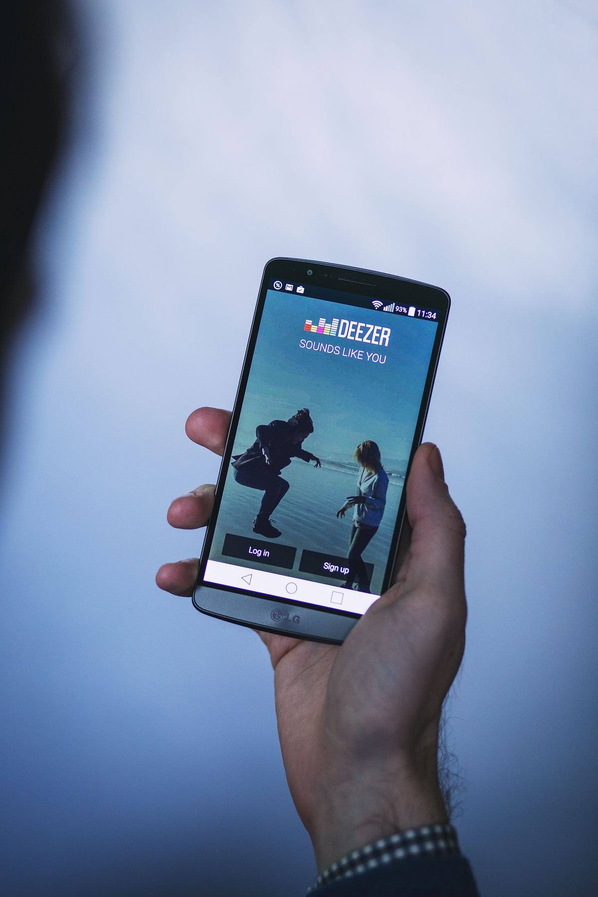 Hand holding a smartphone showing a mobile app login screen